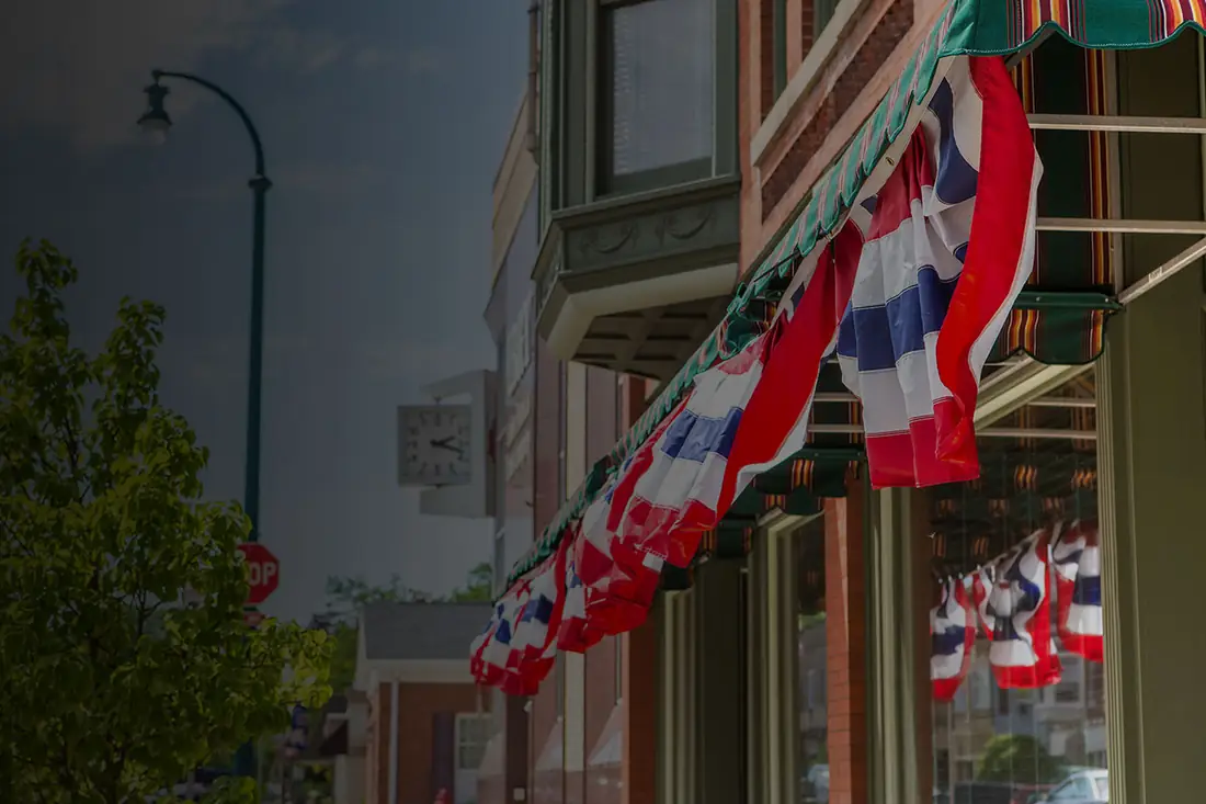 Bunting hung along a shopfront awning on a brick high street.