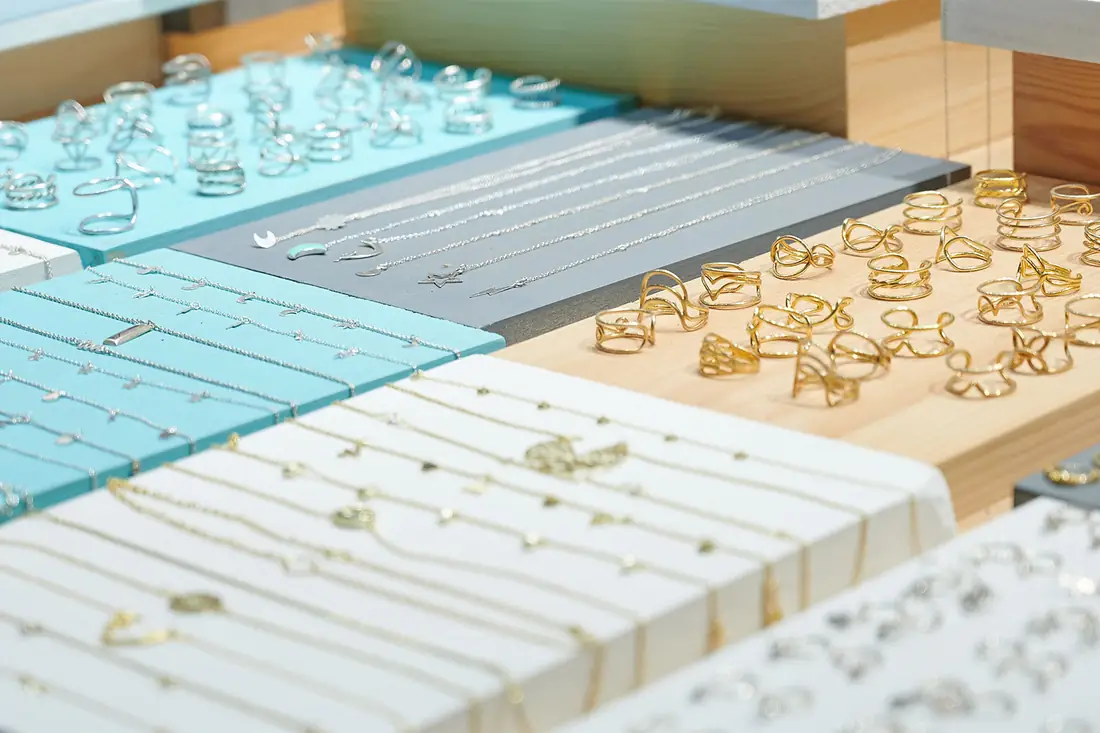 Rings and necklaces laid out in rows on a jeweller's display.