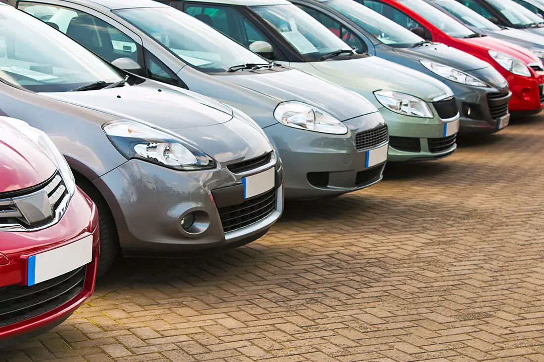 A line of cars for sale on a brick-paved forecourt.